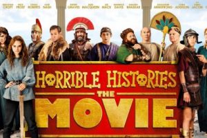 The Horrible Histories Movie poster, showing big yellow writing on a red background, and the various characters from the film surrounding it